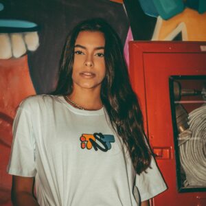 Stylish woman posing in streetwear against colorful graffiti backdrop, showcasing urban fashion.